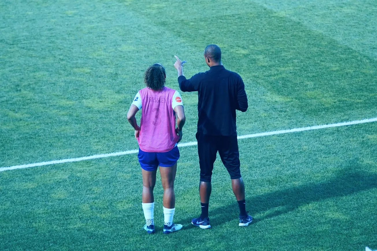 A coach talking with a player on a sports field
